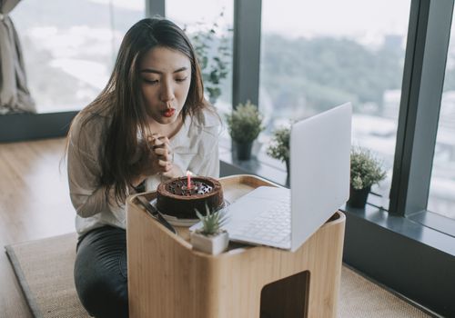 一名亚裔中国年轻女性用笔记本电脑在线视频电话与朋友庆祝自己的生日