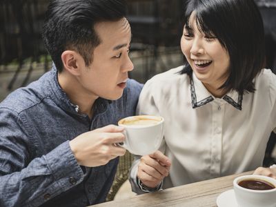 中国女人笑男朋友的嘴唇上有咖啡泡沫