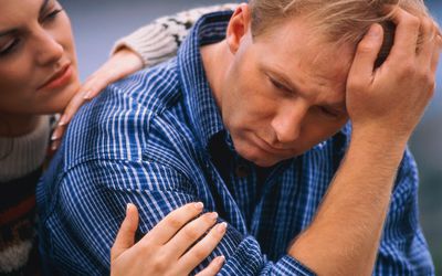 男子双手抱着头，背后的女人