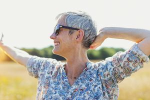 热情的老妇人在阳光明媚的田野里伸出双臂