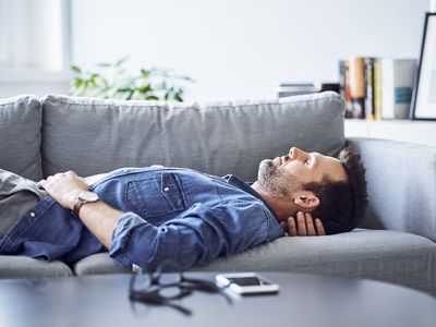 一个男人闭着眼睛躺在沙发上。