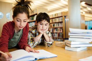 在图书馆做学校项目的男孩和女孩