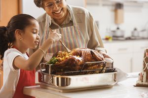 Grandmother and grand daughter cooking a stuffed turkey