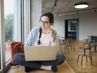 使用膝上型计算机的女性大学生，看在学生休息室的窗口