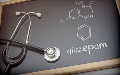 Chemical formula of diazepam written with chalk on a blackboard next to a stethoscope, conceptual image