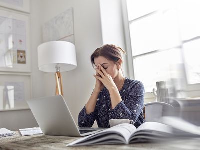 疲倦，膝上型计算机的强调的女实业家有头的头在手上