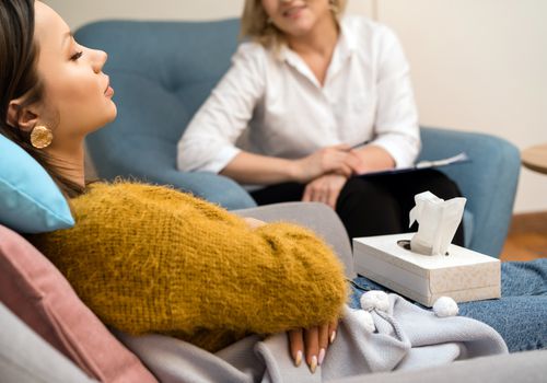 女人坐在一把椅子上，在催眠治疗时从她的治疗师队