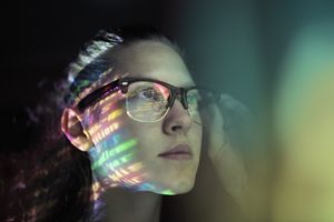 Girl with glasses and colorful code on her face.