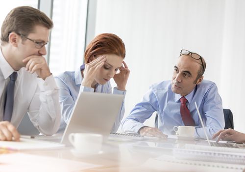 Serious boss talking to businesswoman in conference room