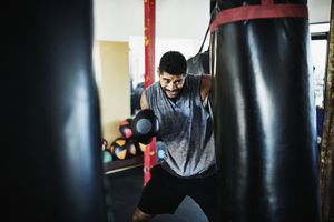 male boxer punching heavy bag in gym