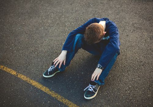 有头的沮丧的年轻男孩在他的膝盖