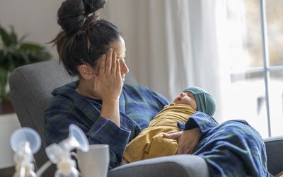 疲倦的新母亲抱着她的宝宝