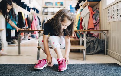 女孩在幼儿园衣帽间坐在板凳上穿鞋全长