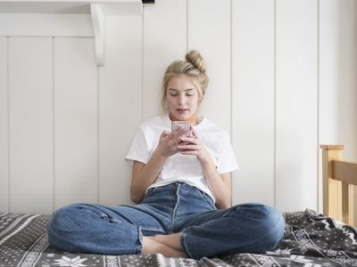 少女拿着手机坐在床上