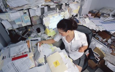 看通过纸的女实业家在杂乱的书桌上，高的看法