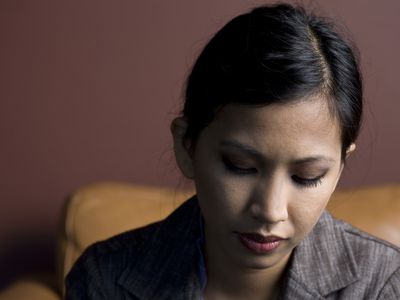 Sad Young Asian Woman Sitting and Looking Down