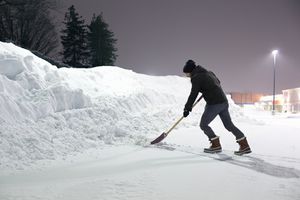 晚上，人们用铲子把雪推向雪堆。