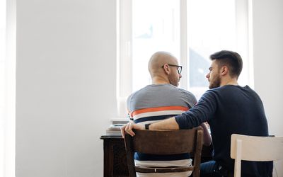 一对同性恋夫妇坐在客厅的桌子上聊天。