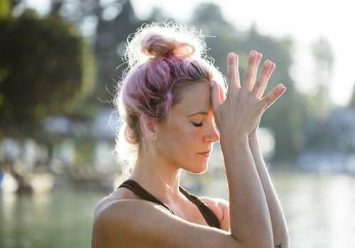 Woman with dyed hair meditating at a lake