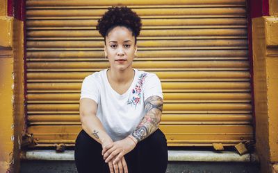 坐下的bipoc妇女的画象“class=