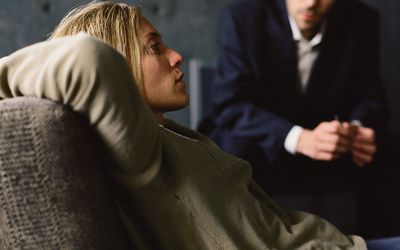 斜倚在长沙发，看她的心理学家的少妇在背景中。