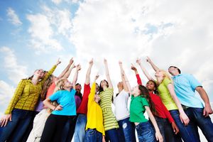 group of elementary and middle school children pointing at clouds in sky