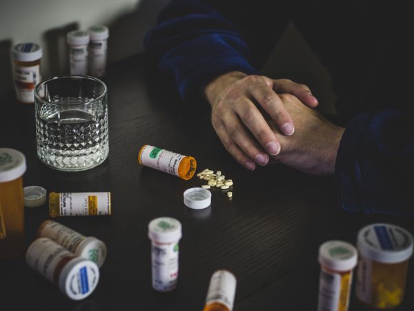 man surrounded by pill bottles