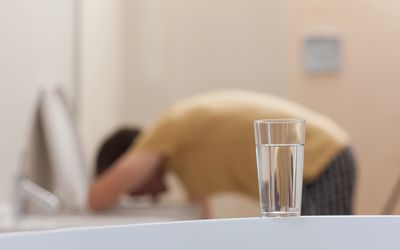 杯在柜台的水与呕吐在洗手间的人在背景中