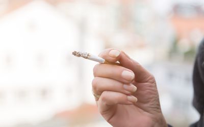 妇女抽烟的香烟的播种的手