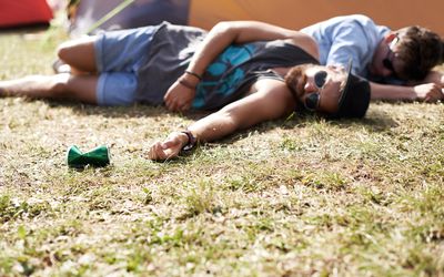 two men passed out in the grass at an outdoor festival