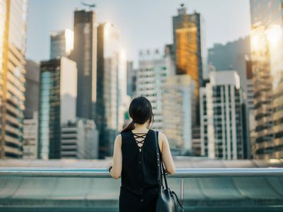 女人的后视图在城市城市景观的天空