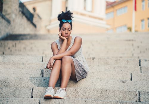 一个悲伤的女人坐在外面的台阶上。