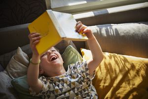 男孩躺着看书，笑着
