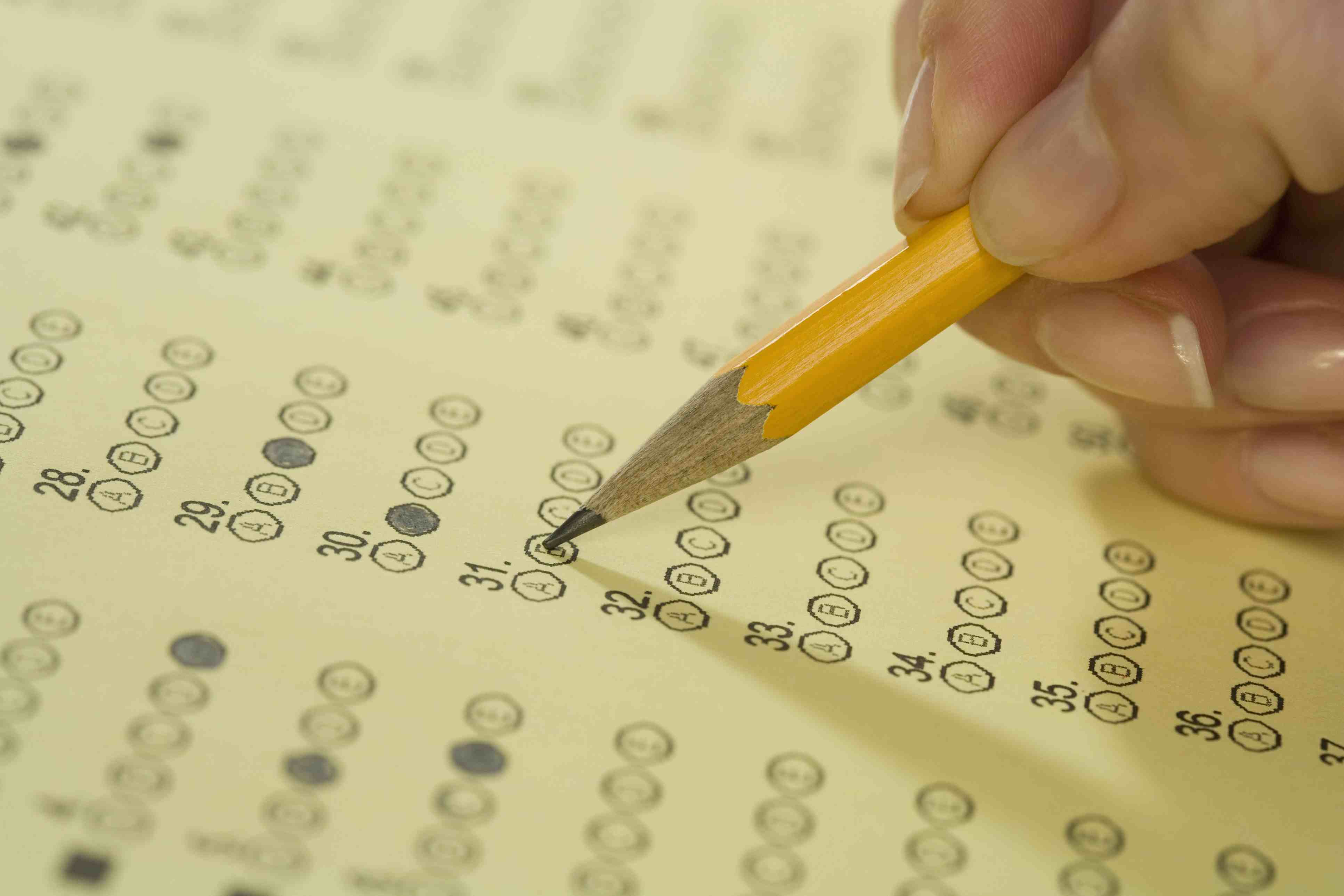 Woman's hand, holding pencil, marking answer bubble on test sheet