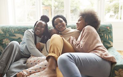 圣诞节期间，快乐的年轻女子坐在家里的沙发上拥抱女孩