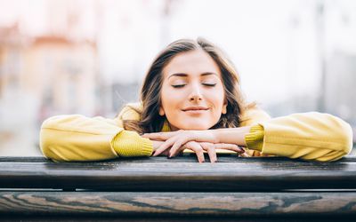 倾斜反对与她的眼睛的栏杆的妇女关闭和微笑