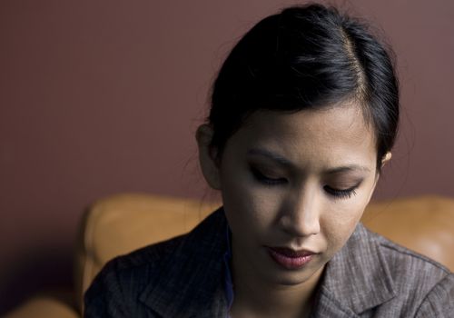 Sad Young Asian Woman Sitting and Looking Down