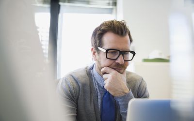 在膝上型计算机手上的被聚焦的商人在下巴