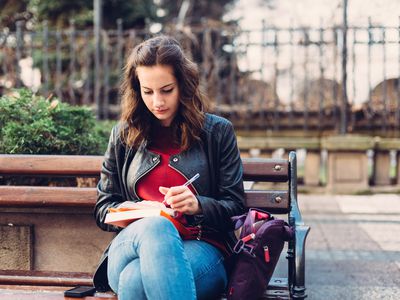 年轻女子在外面的笔记本上写字