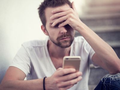 一个留着胡子的白人悲哀地看着手机