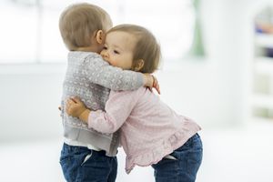 Two twin baby girls are playing together and hugging at daycare