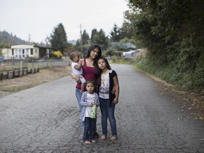 有她的三个孩子的一个土着女人的照片。