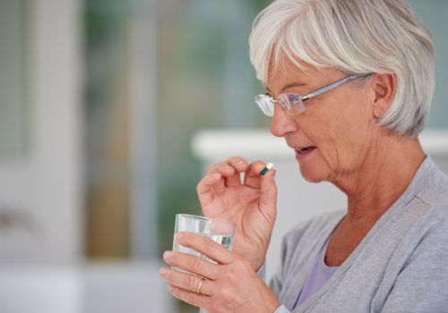 Senior woman taking a pill with water