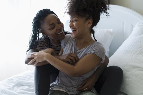 女同性恋夫妇放宽在床上，拥抱，笑