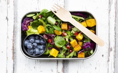 混合沙拉用烤豆腐，红甘蓝，石榴种子，蓝莓和姜黄在午餐盒