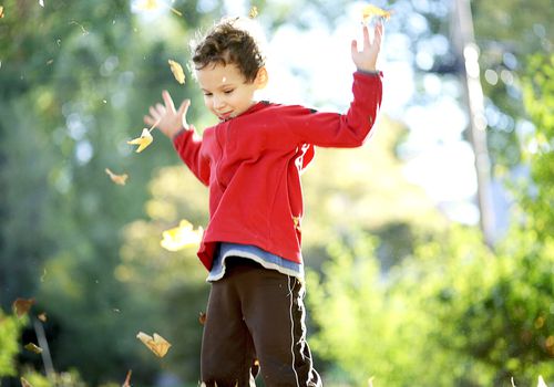 Child tossing autumn leaves into the air