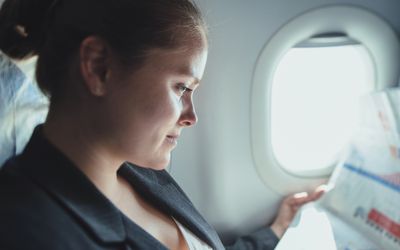 Business woman reading news in plane.