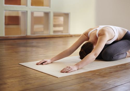 Woman on a yoga mat in a studio doing child's pose