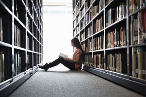 Woman sitting on the floor in the library stacks reading