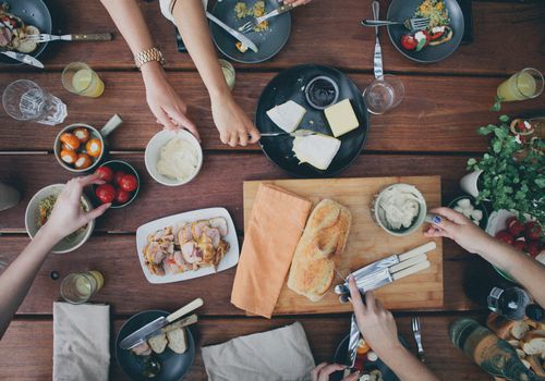 overhead view of people's hands reaching for food at table